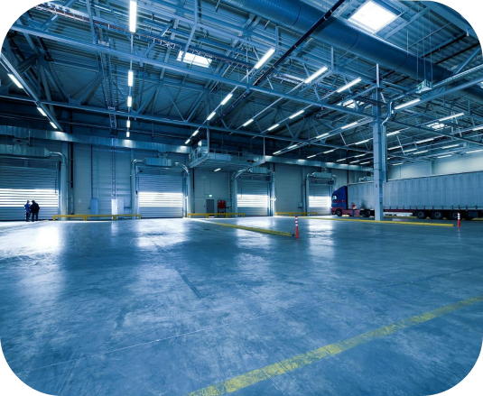 Empty warehouse with large loading bay doors and industrial lighting.
